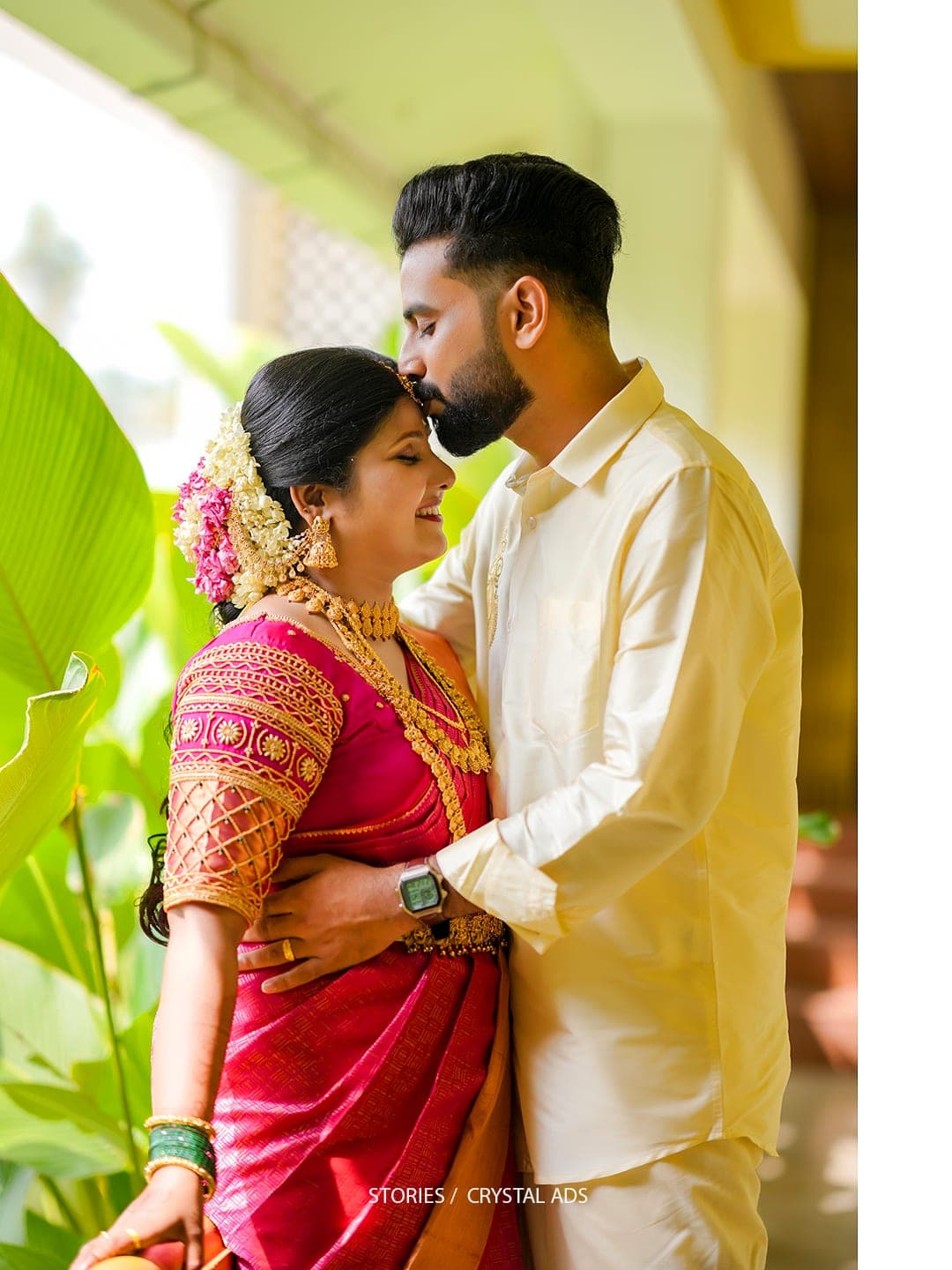 Groom kissing bride's forehead in traditional Kerala wedding attire